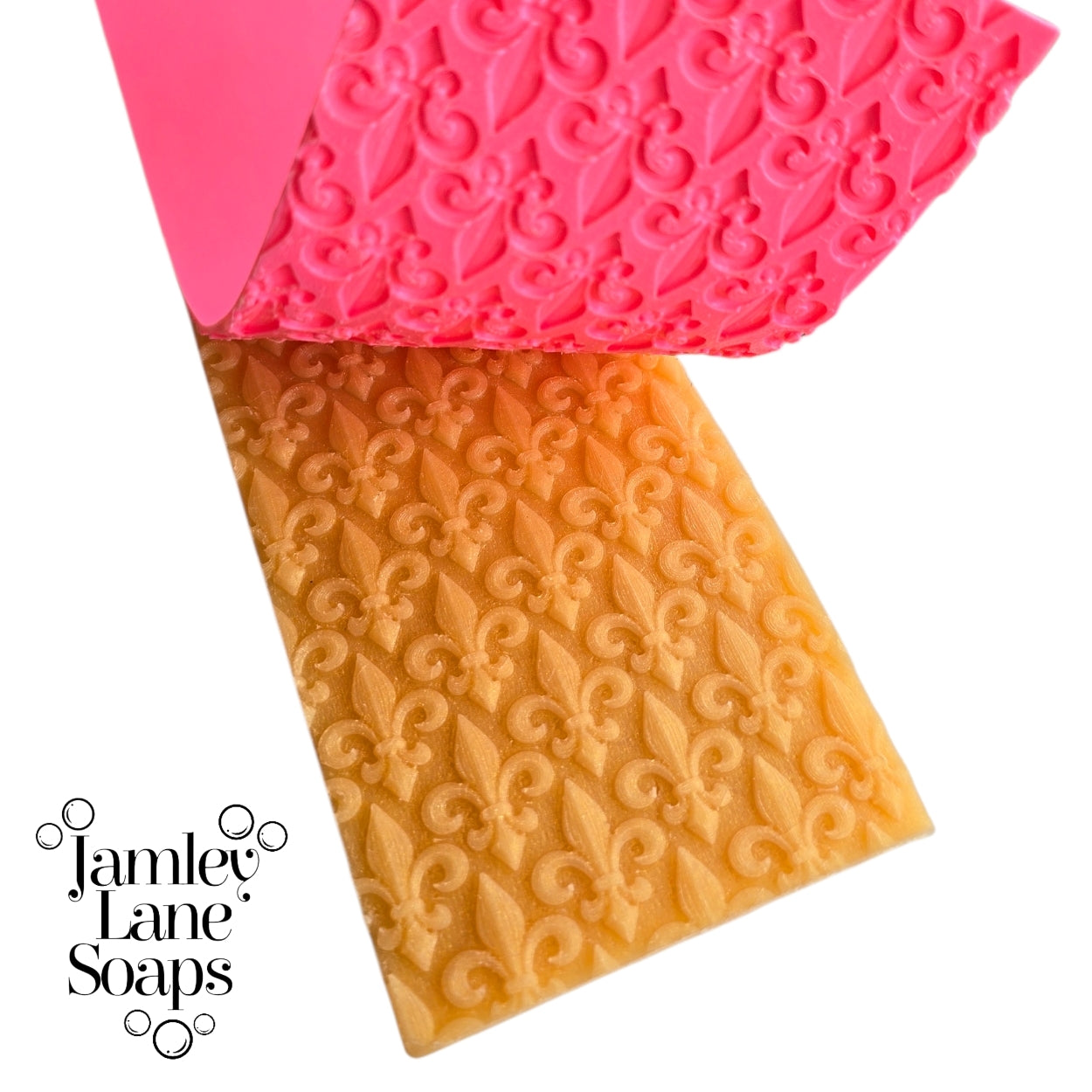 repeating fleur de lis pattern artisan polymer impression mat being peeled away from a gold melt and pour soap top.