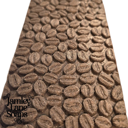Close-up of the coffee bean design that's the result of using the impression mat in the listing with 'Jamley Lane Soaps' branding in the corner of the photo.