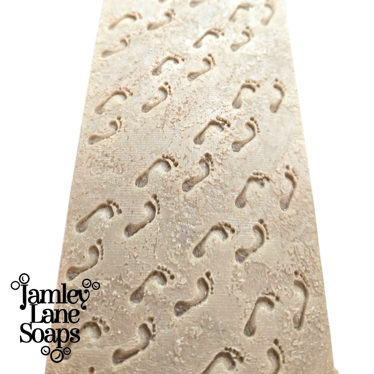 loaf of soap close up featuring the sandy footprints pattern created as a result of the impression mat in the listing and featuring 'Jamley Lane Soaps' branding