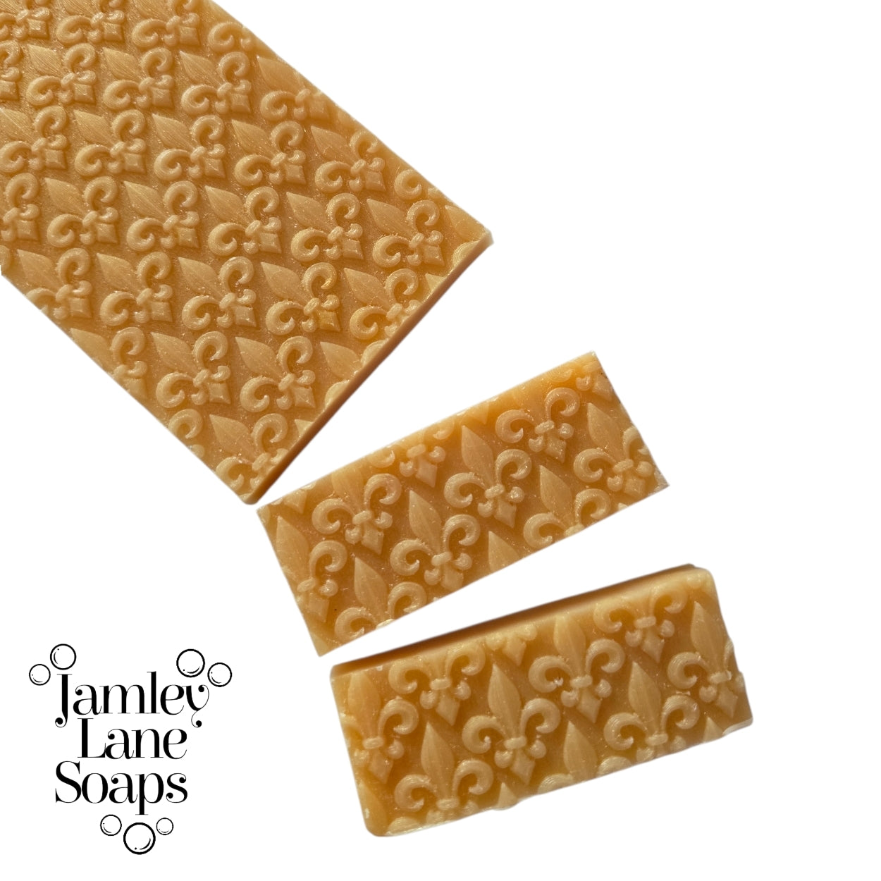 repeating fleur de lis pattern artisan polymer impression mat on  a gold melt and pour soap top that's been cut to show a 1" bar.