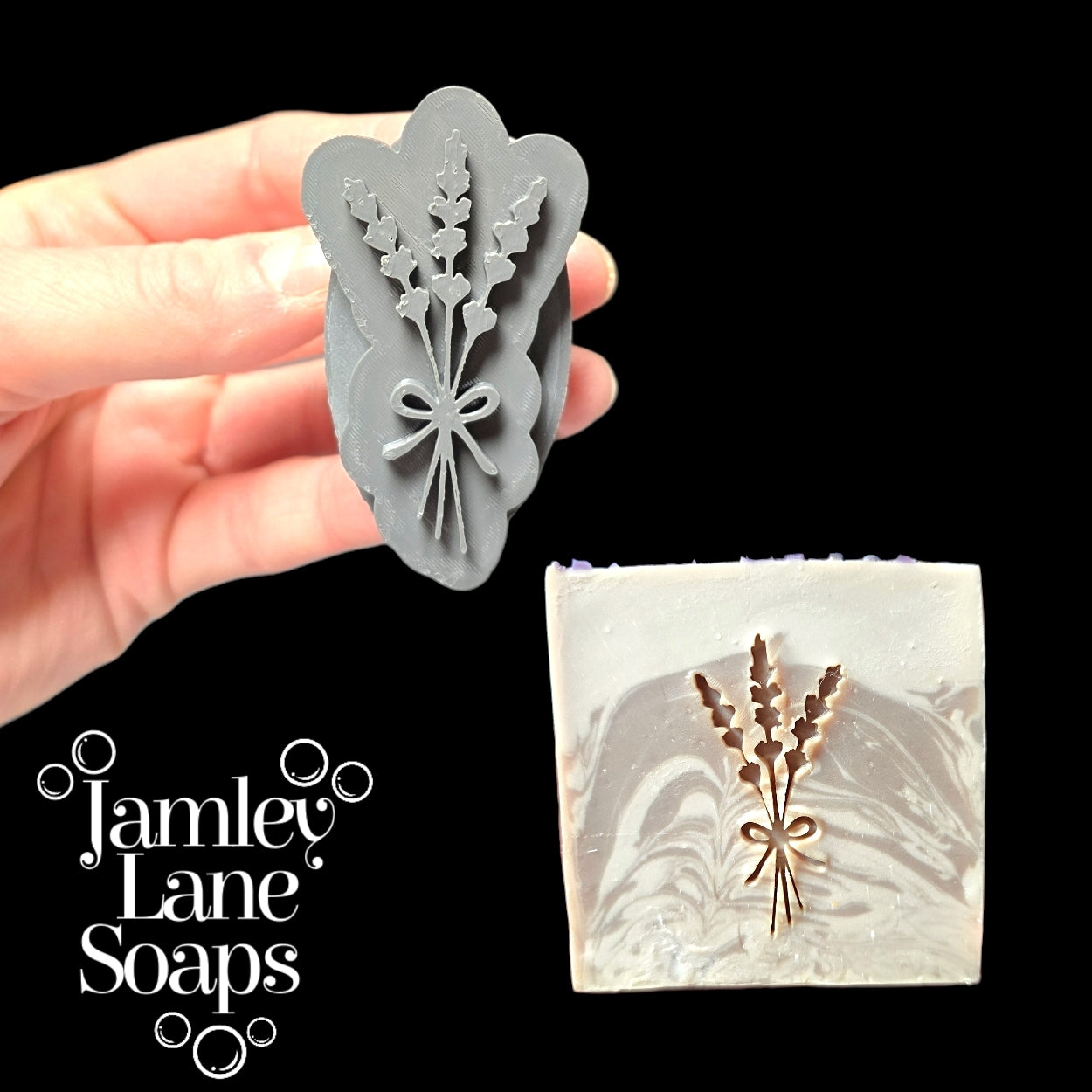 Gray stamp with lavender floral design held by a hand, next to a bar of soap with the same design, on a black background with 'Jamley Lane Soaps' branding.