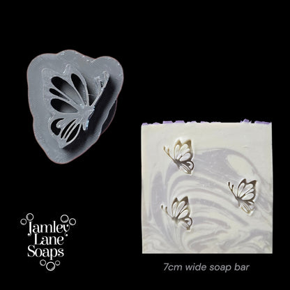 Butterfly-shaped soap stamp and soap bar with butterfly design on a black background, featuring Jamey Lane Soaps branding.