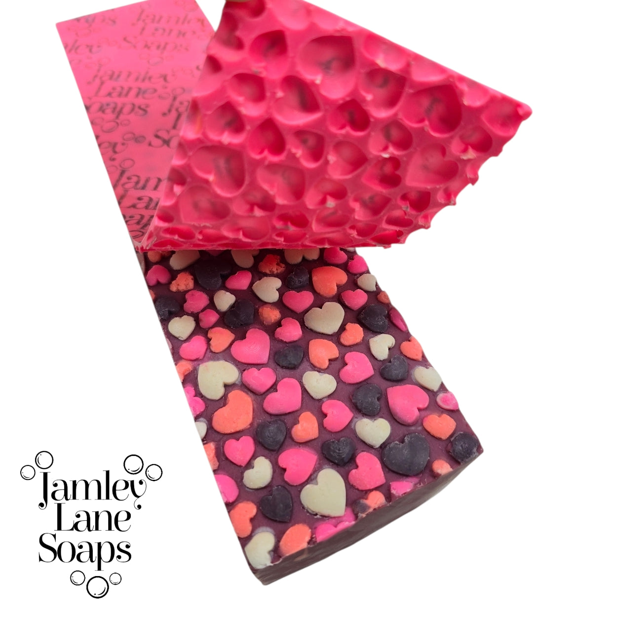 Heart-patterned soap bar with pink artisan polymer impression mat being peeled away to reveal a bubble heart 3d pattern and 'Jamley Lane Soaps' branding on a white background