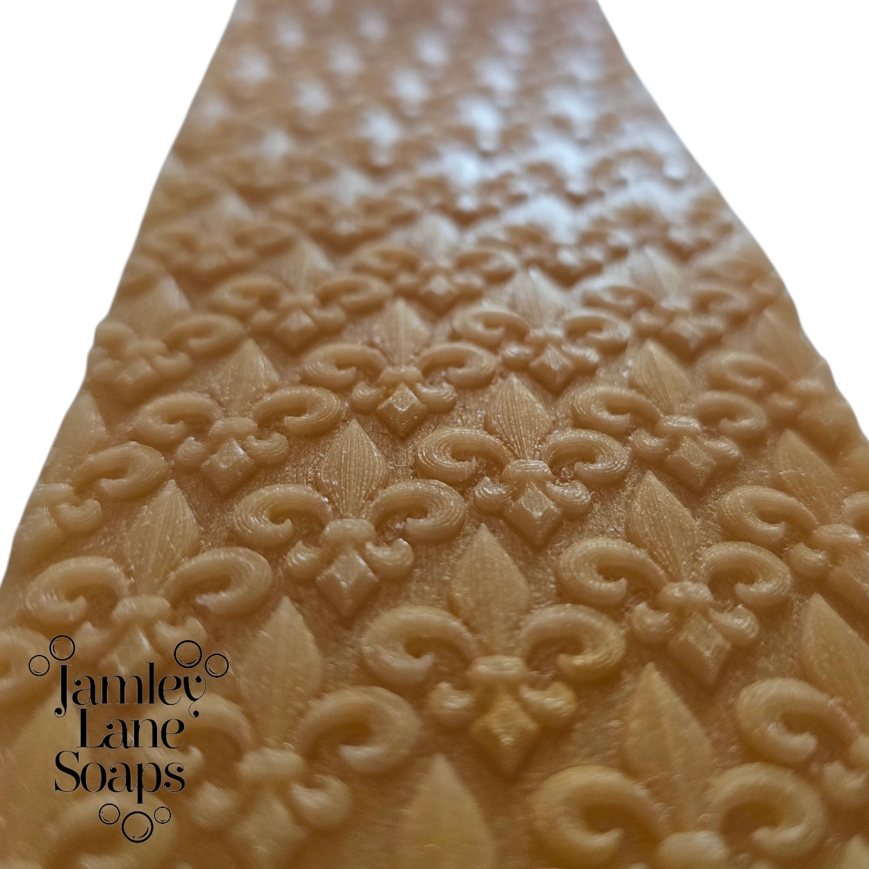 Decorative soap with intricate fleur de lis pattern and 'Jamey Lane Soaps' branding on a white background