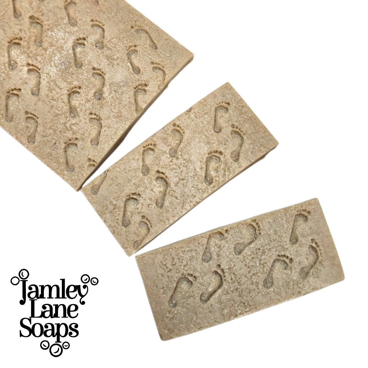 a loaf of soap featuring the sandy footprint pattern cut into 2 one inch size bars to showcase the size of the pattern on a avarage 1" size  bar of soap.