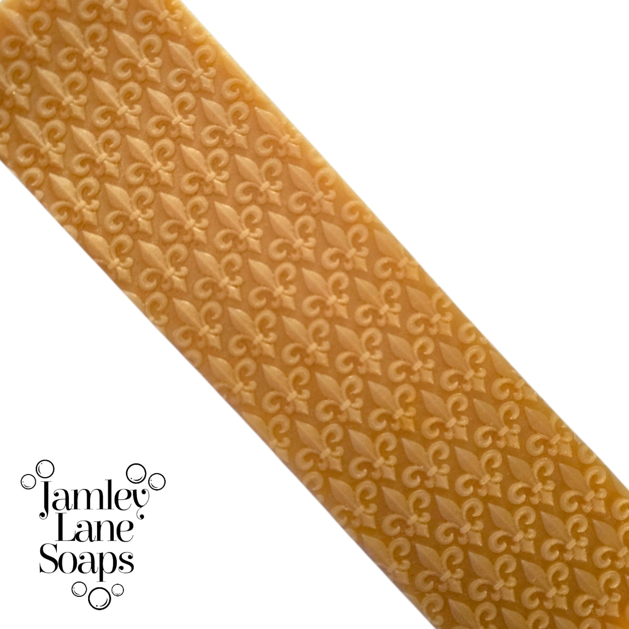 repeating fleur de lis pattern artisan polymer impression on a gold melt and pour soap top.