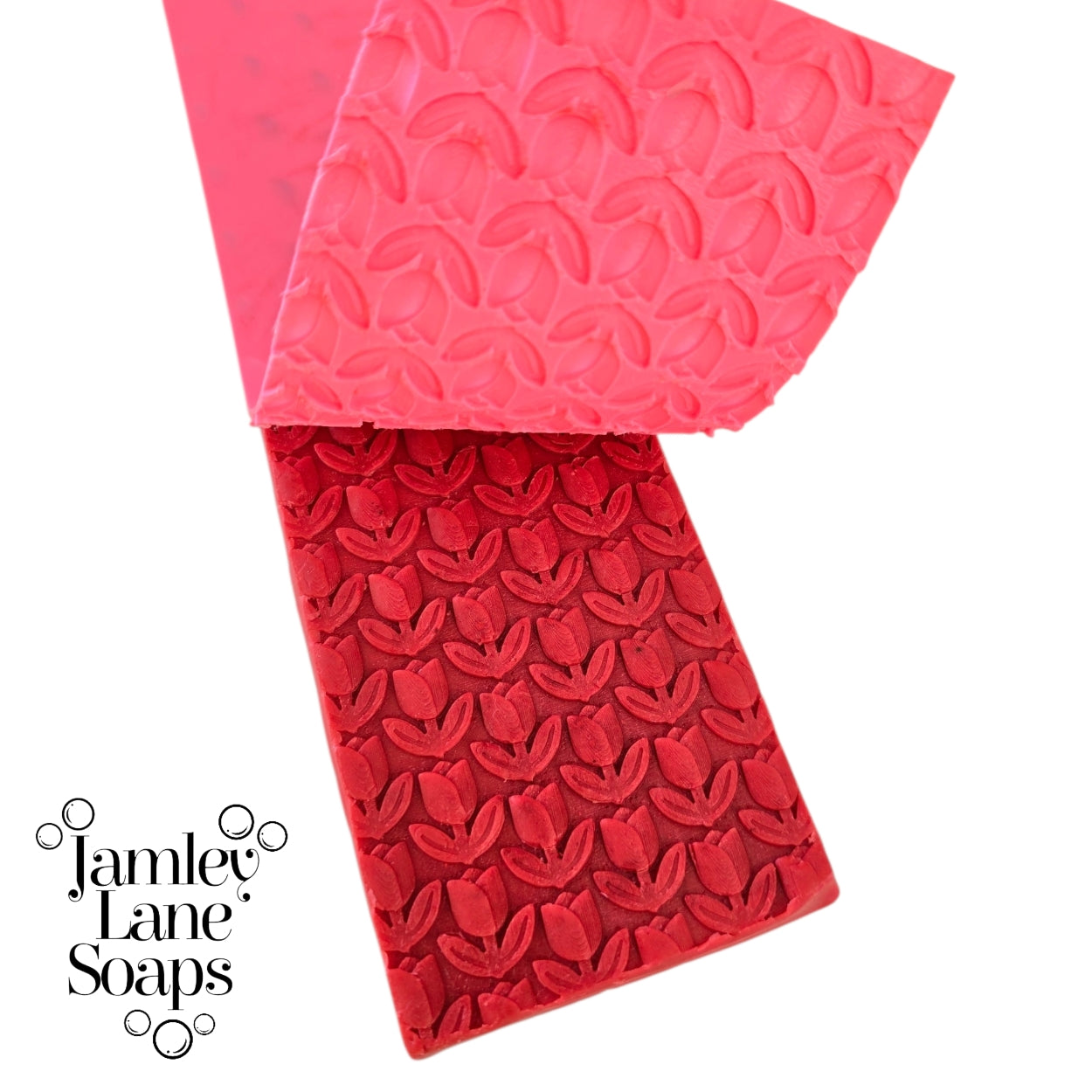 repeating tulip artisan polymer impression mat being peeled back from a red melt and  pour soap top on a white background, branded with 'Jamley Lane Soaps'.