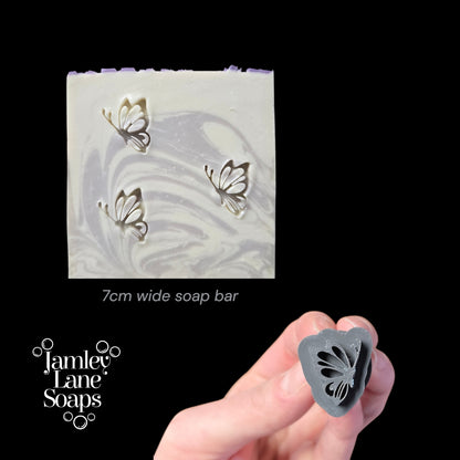 Soap bar with butterfly designs and a hand holding a butterfly-shaped stamp, branded as Jamey Lane Soaps.