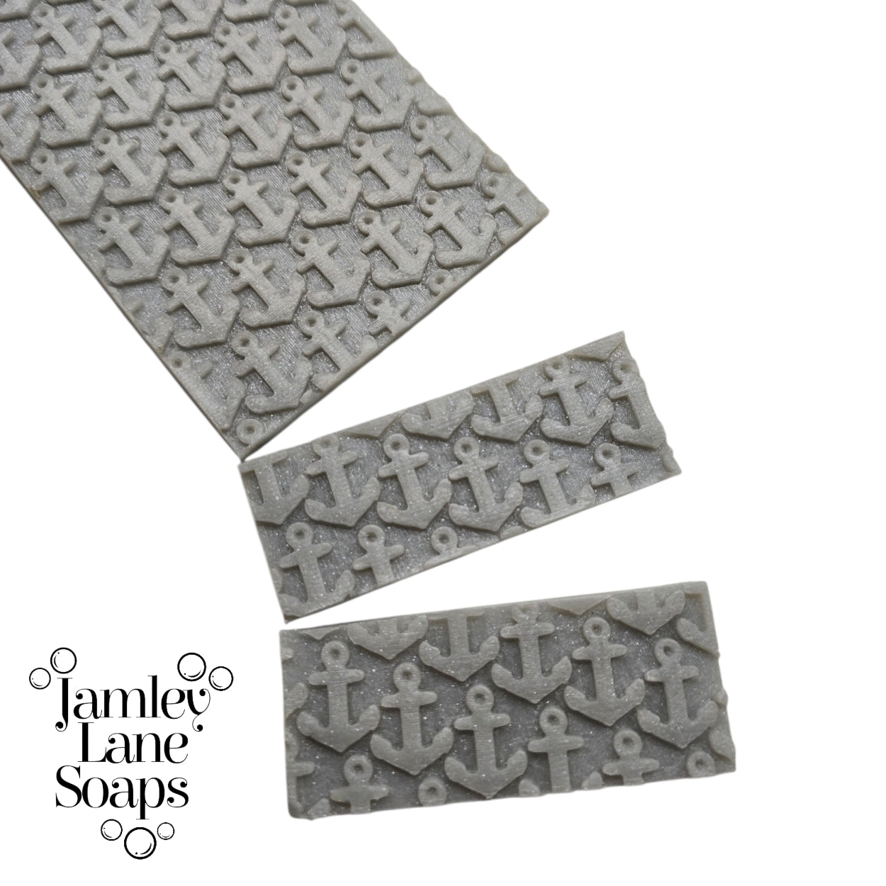 Gray textured soap with repeating anchor pattern on silver melt and pour soap top that's been cut to show a 1" bar